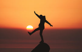 Man balancing on a rock at sunset